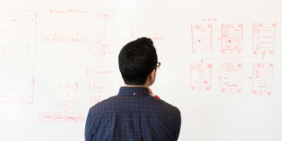 A person actively planning or strategizing on a whiteboard, representing the intentional approach to building a personal reading journey.