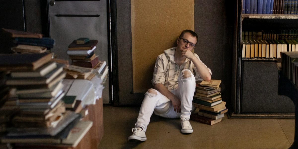 A person looking at a bookshelf, deep in thought about which book to choose next.