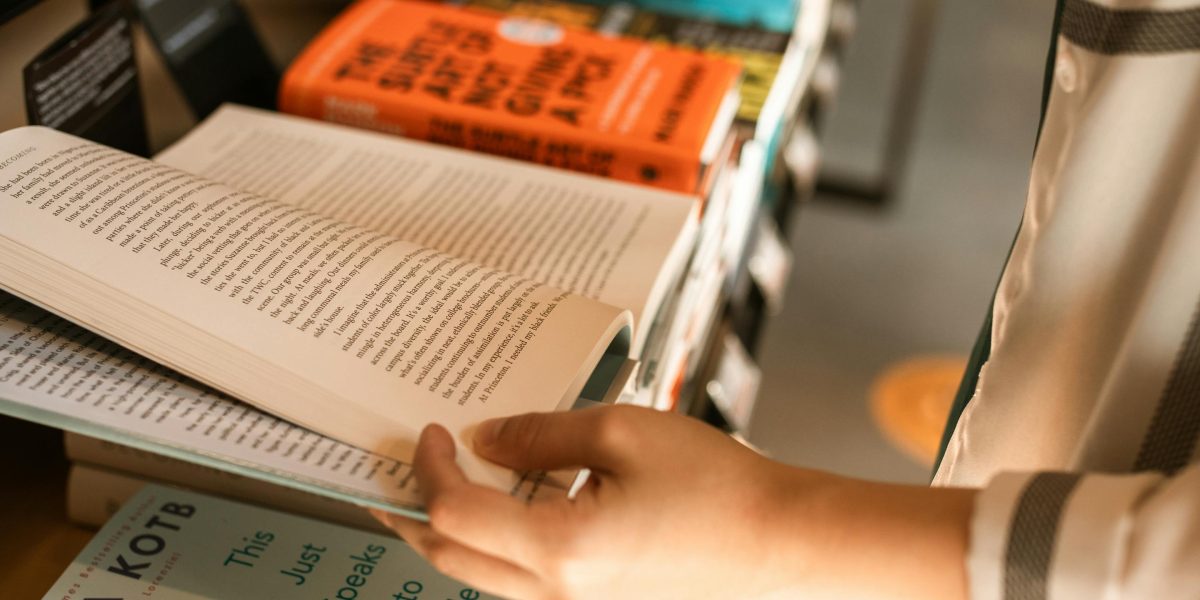 A reader thoughtfully exploring options in a bookstore's fantasy section, seeking their next compelling story.