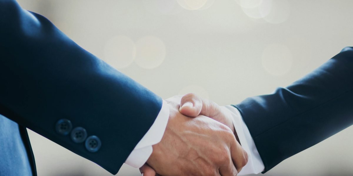 Two people shaking hands warmly, symbolizing connection, respect, and bridging differences.