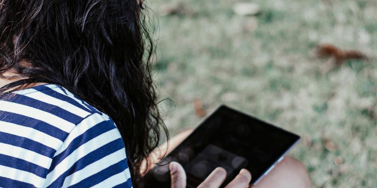 A person attentively watching content on a tablet or phone for book recommendations.